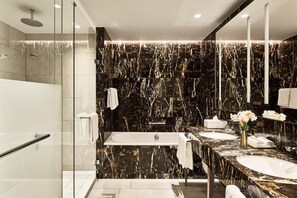 A modern bathroom with a large bathtub, two sinks, and a glass shower enclosure. - Hyatt Regency Amsterdam (Amsterdam)