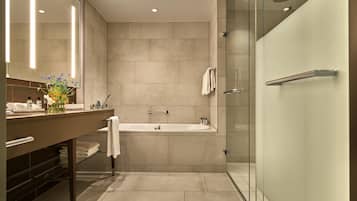A modern bathroom with a glass-enclosed shower, a freestanding bathtub, and a vanity with a mirror and towel rack.