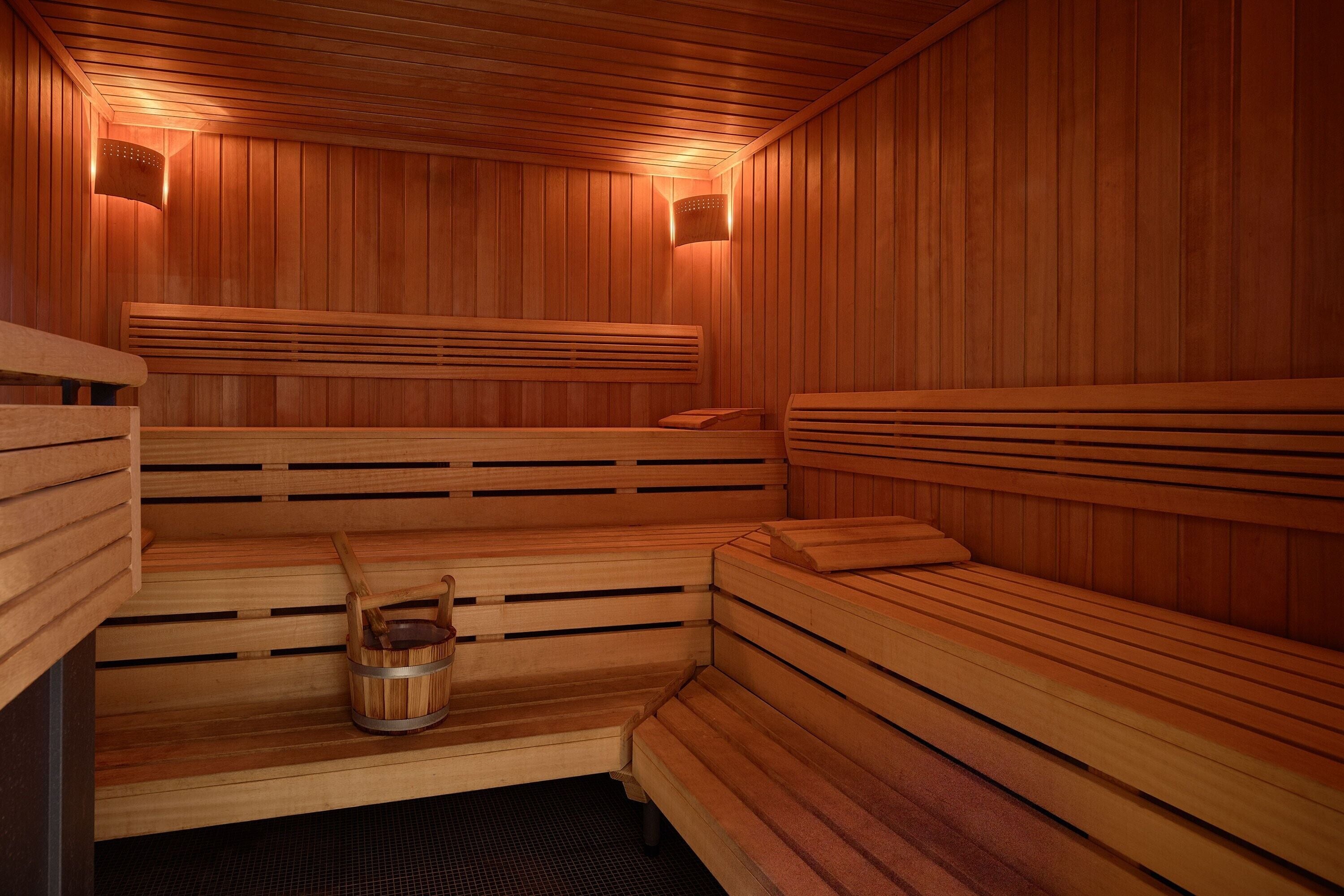Een sauna met houten banken en een houten emmer.