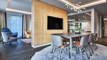 A modern dining area with a large table, chairs, and a flat-screen TV mounted on a wall.