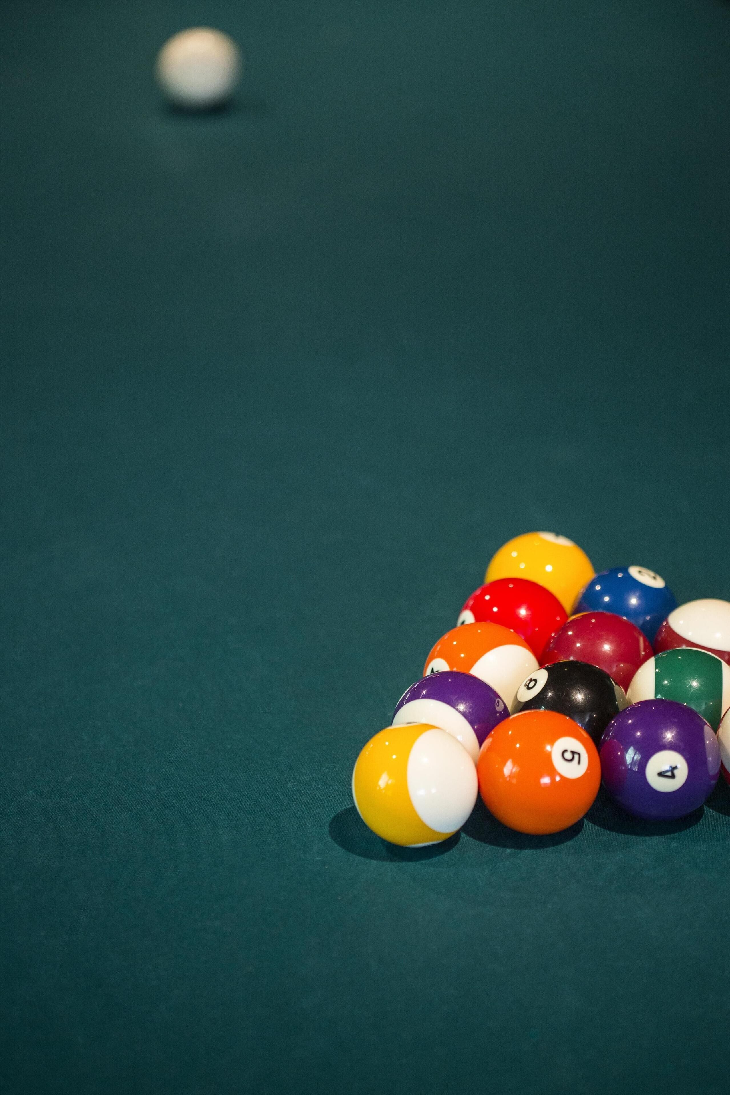 A pool table with a green felt surface and a collection of billiard balls in various colors and numbers.