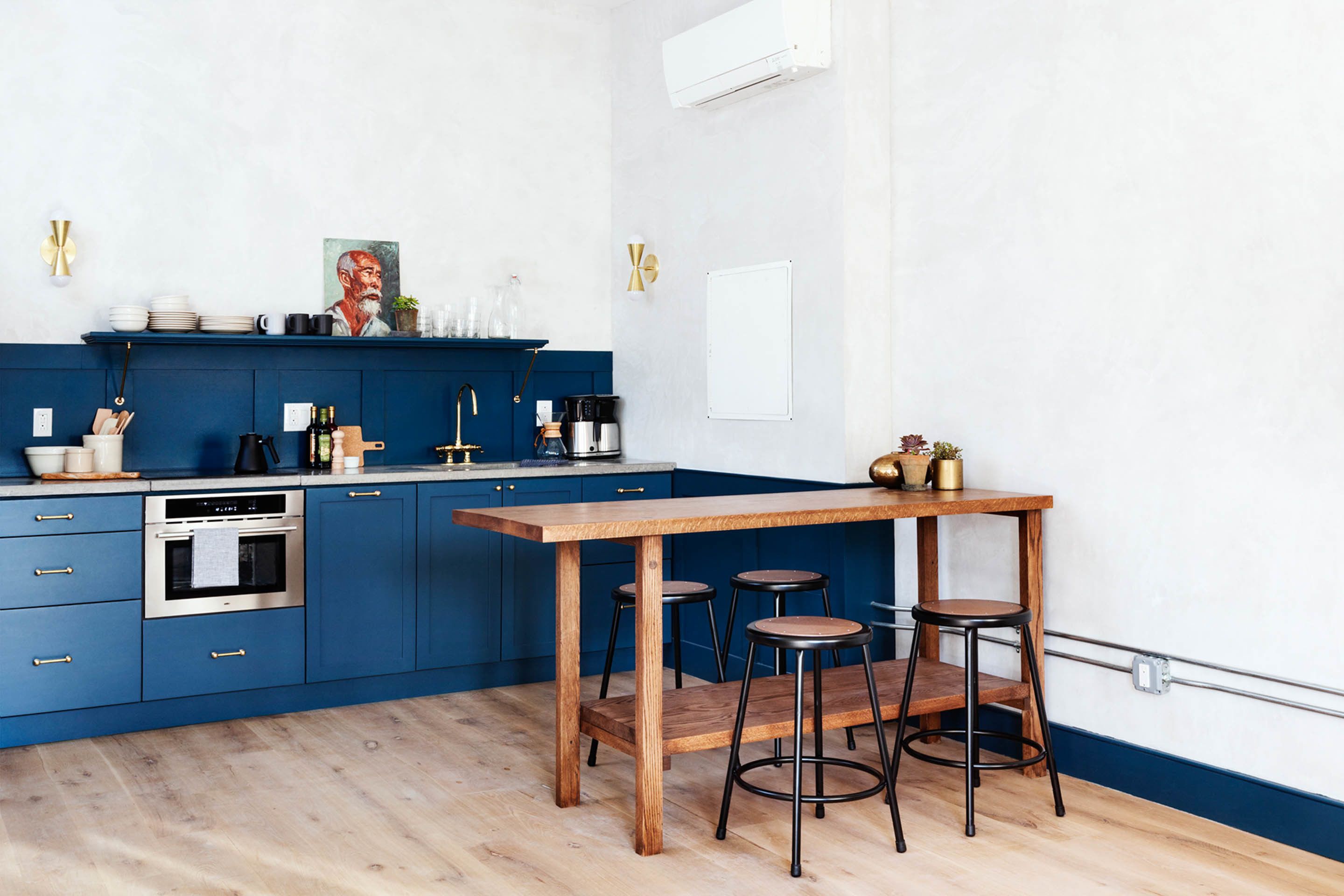 Eine moderne Küche mit blauen Schränken, einem Holztisch und Barhocker.