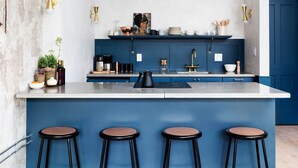 Una cocina moderna con una pared azul de acento, una isla central con taburetes y diversos electrodomésticos.