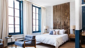Un dormitorio con una cama grande, una silla, una mesita y un revestimiento de pared de madera.