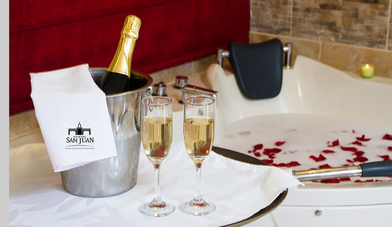 En champagnekylare med glas, en handduk och ett ljus, placerat i ett badrum.