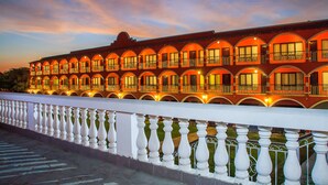 A hotel with multiple balconies and arched windows, featuring a white balustrade. - HACIENDA SAN JUAN RESORT   (San Juan Bautista)