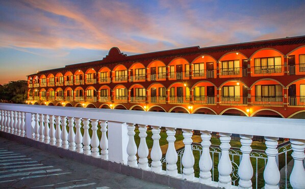 A hotel with multiple balconies and arched windows, featuring a white balustrade. - HACIENDA SAN JUAN RESORT (San Juan Bautista)