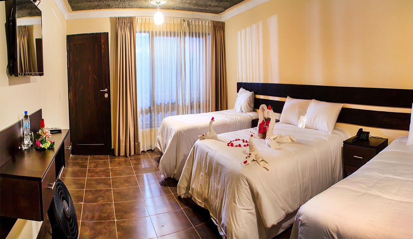 A hotel room with two beds, a desk with a fan, a mirror, and a door.