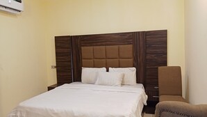 Una habitación de hotel con una cama grande, un cabecero de madera, una mesita de noche y una silla.