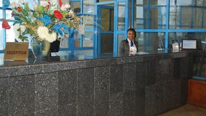 Un mostrador de recepción con un cartel que dice "RECEPTION" y un jarrón con flores.