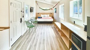 A hotel room with a bed, a desk, a chair, a TV, and a ceiling fan. - Gravity Haus Westport (Westport)