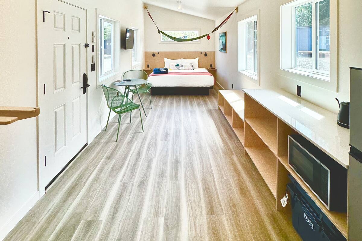 A hotel room with a bed, a desk, a chair, a TV, and a ceiling fan.