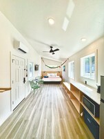 Una habitación de hotel con cama, escritorio, silla, televisor y ventilador de techo.