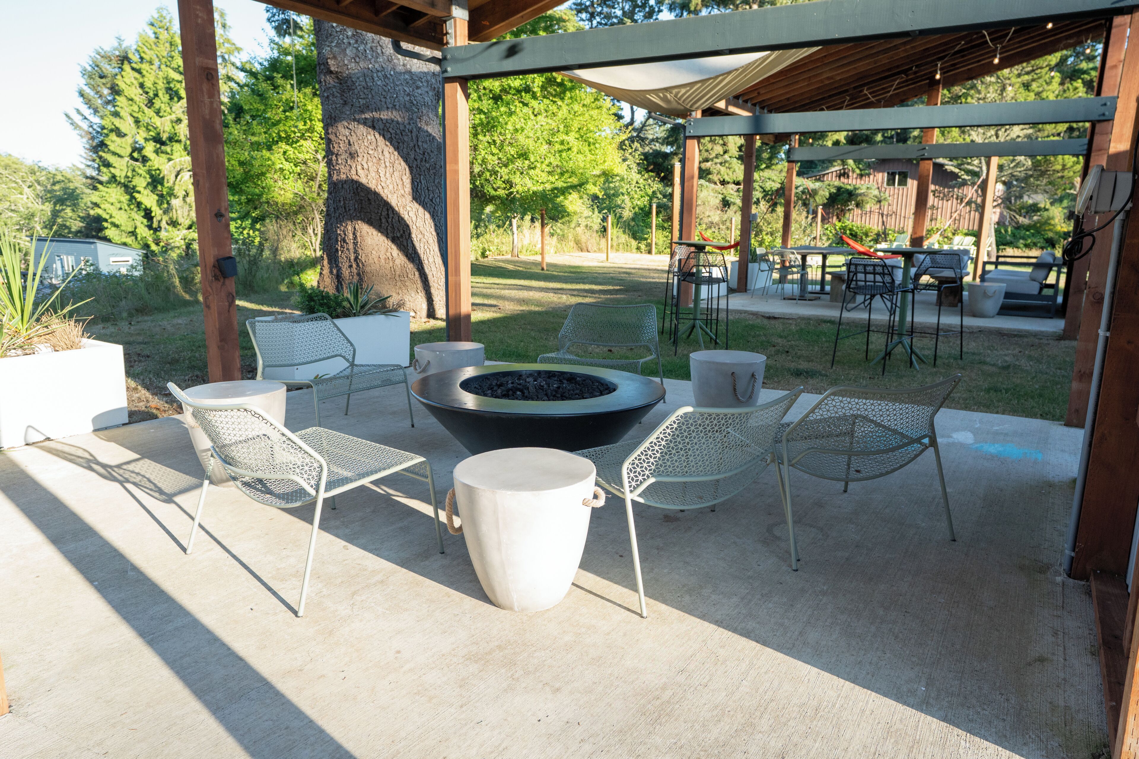 A covered patio area with outdoor seating, a fire pit, and a pergola structure.