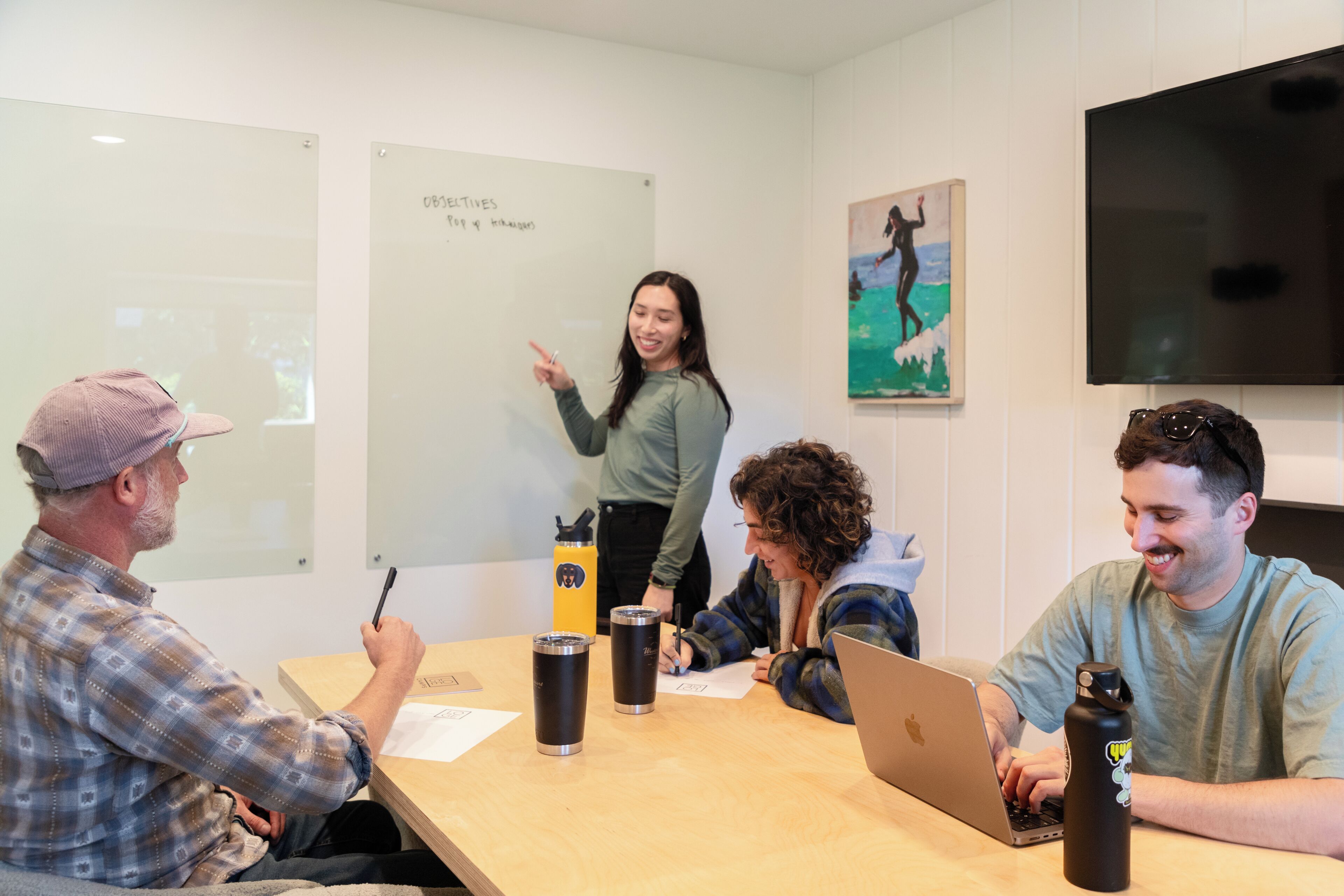 A meeting room with a whiteboard, a laptop, and water bottles on a table.