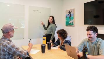 A meeting room with a whiteboard, a laptop, and water bottles on a table.