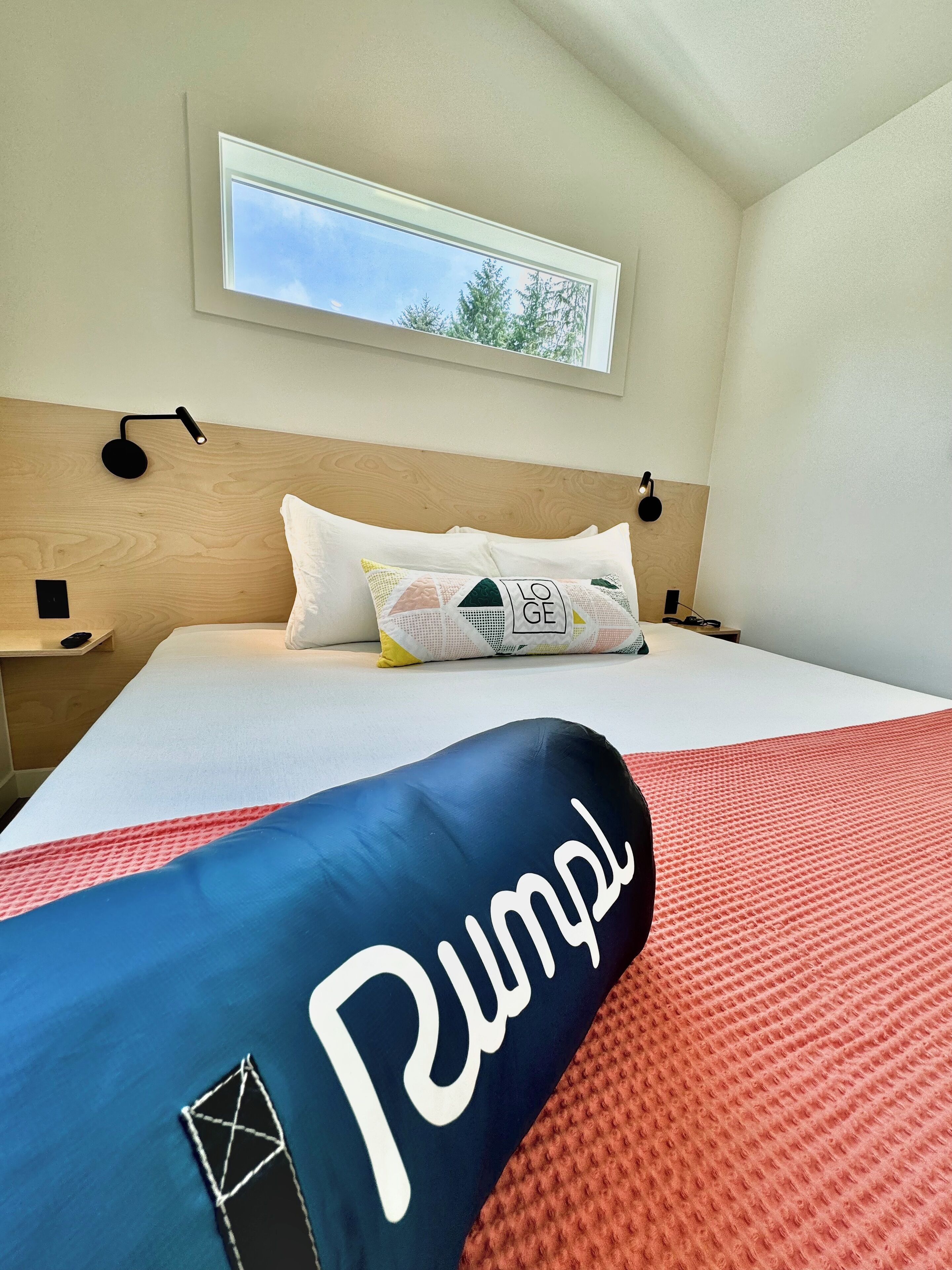 A hotel room with a bed, a window, and a nightstand.