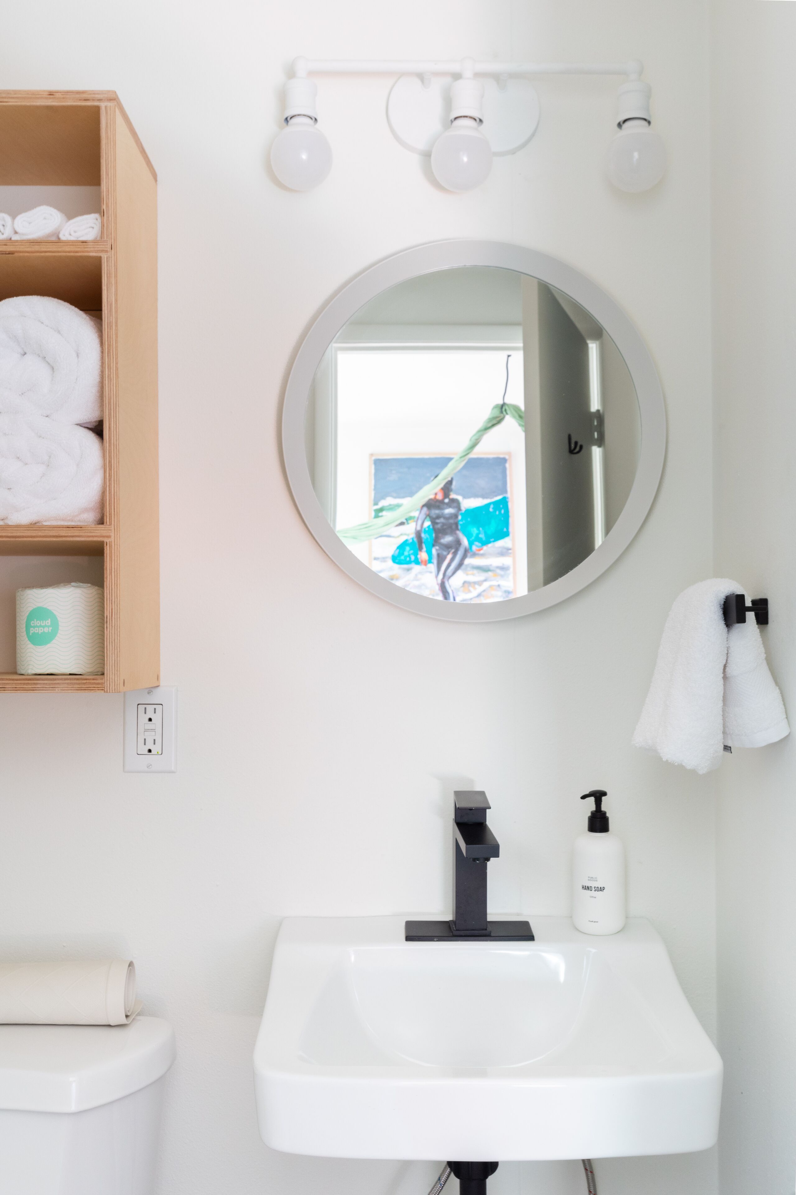Une salle de bain avec un lavabo blanc, un miroir et un porte-serviettes.