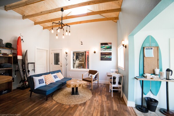 Ein gemütliches Wohnzimmer mit einem blauen Sofa, einem Holztisch und einem Surfbrett an der Wand.