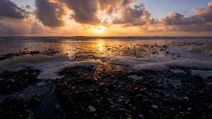 A beach with a sunset, waves, and a rocky shoreline. - Gravity Haus Westport (Westport)