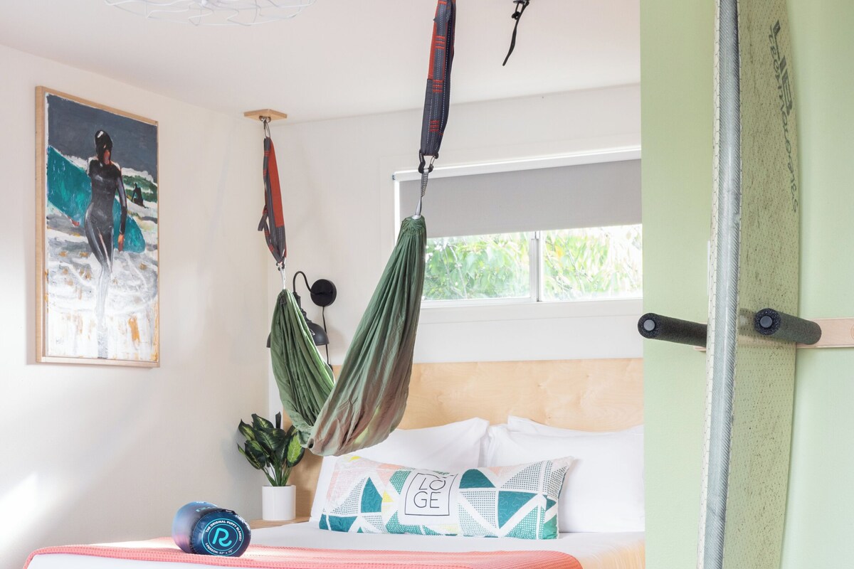 Ein Schlafzimmer mit Bett, Hängematte, Surfbrett und Deckenventilator.