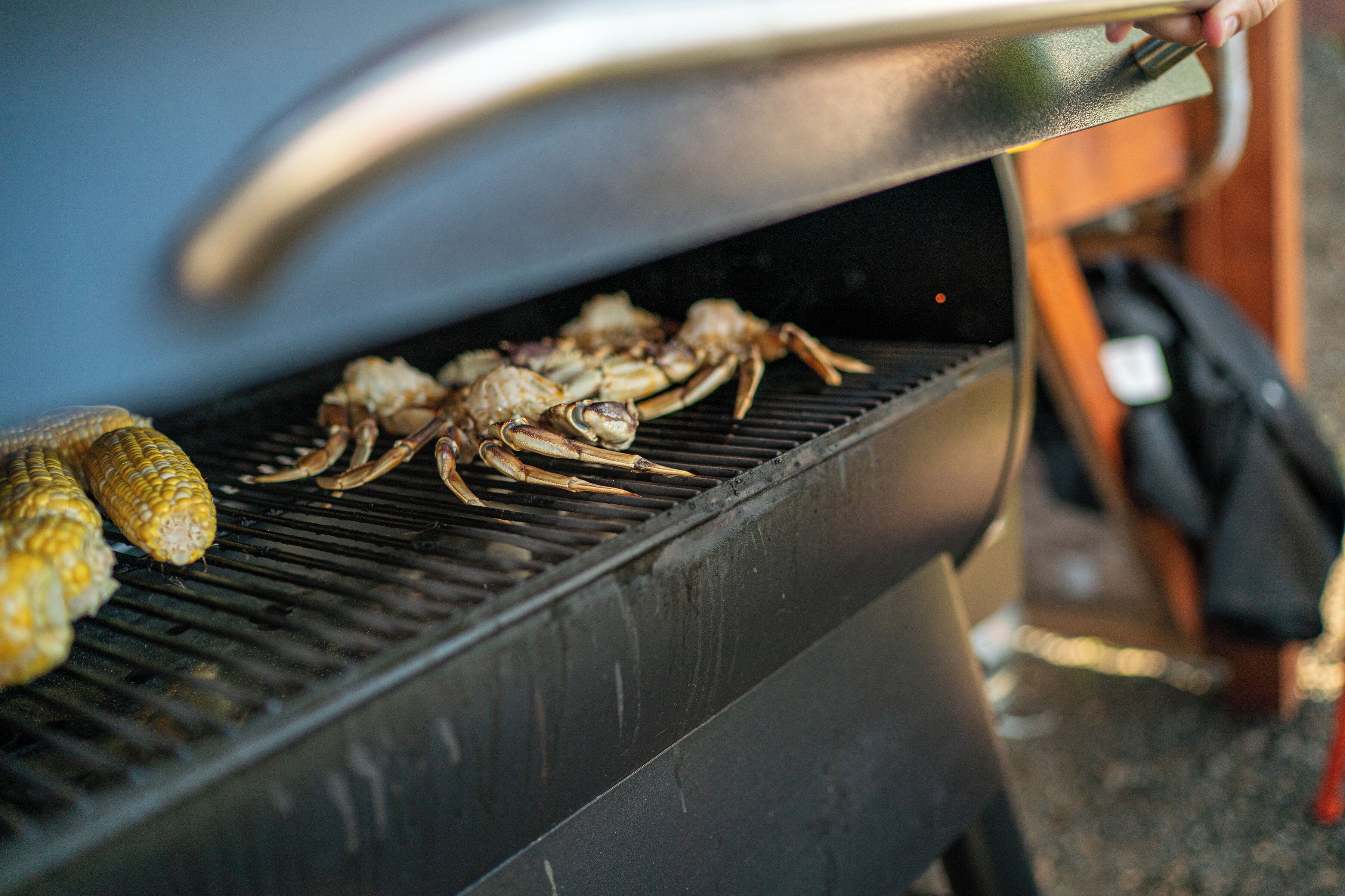 A grill with seafood, including crabs and corn on a grill.