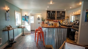 A cozy cafe with a wooden bar, red stools, and a chalkboard menu. - Gravity Haus Westport (Westport)