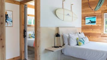 Un dormitorio con cama, mesita de noche, una tabla de surf y una hamaca.
