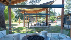 A covered outdoor patio with metal chairs, a fire pit, and a table. - Gravity Haus Westport (Westport)