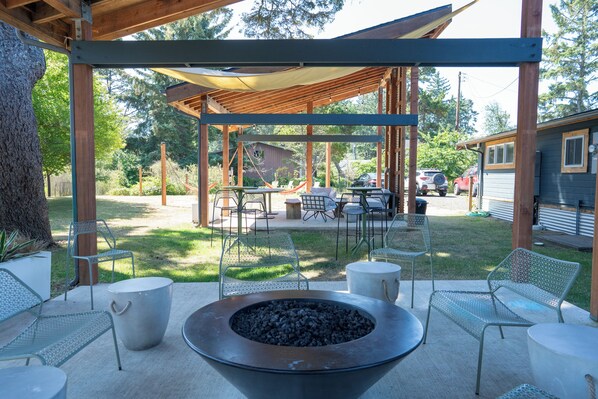 A covered outdoor patio with metal chairs, a fire pit, and a table. - Gravity Haus Westport (Westport)