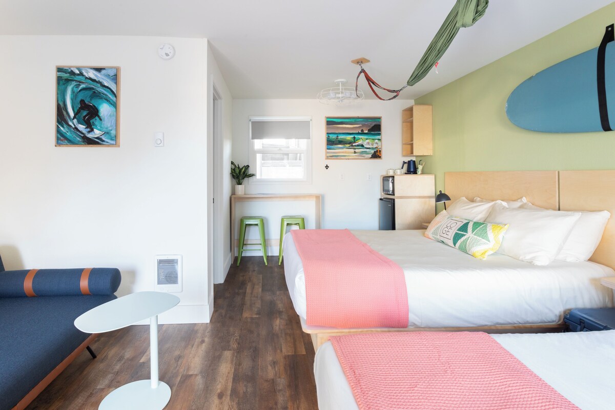A modern hotel room with a bed, bedside table, and a small seating area.