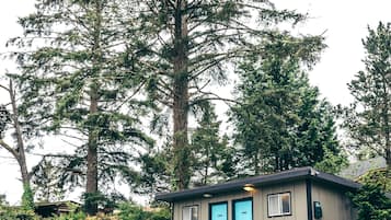 A small cabin with two blue doors, a wooden deck, and a staircase leading up to it.
