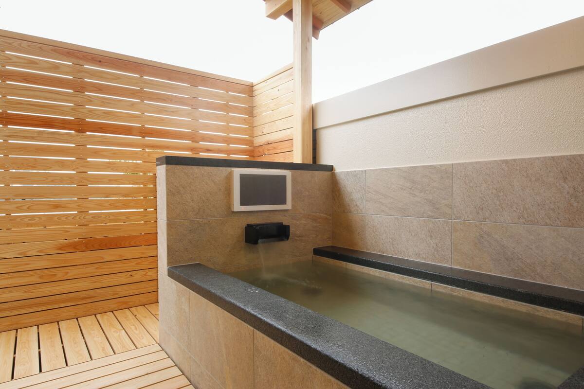 A modern spa area with a wooden slatted wall, a stone-tiled wall, and a glass-enclosed hot tub.