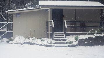 Een klein gebouw met een sneeuwbedekte dak en een trap naar de deur.