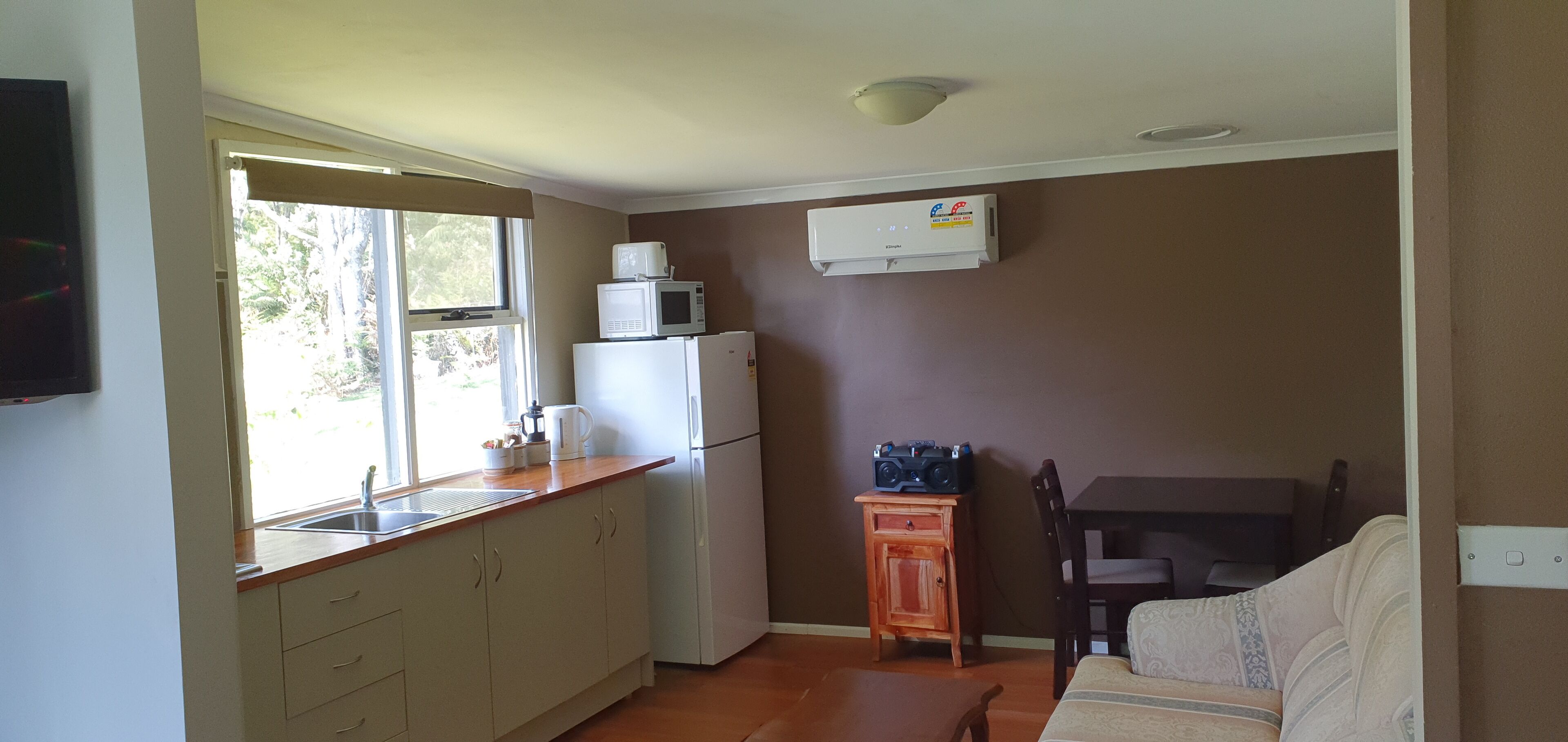 Cocina compacta con refrigerador, microondas y un pequeño armario de madera.