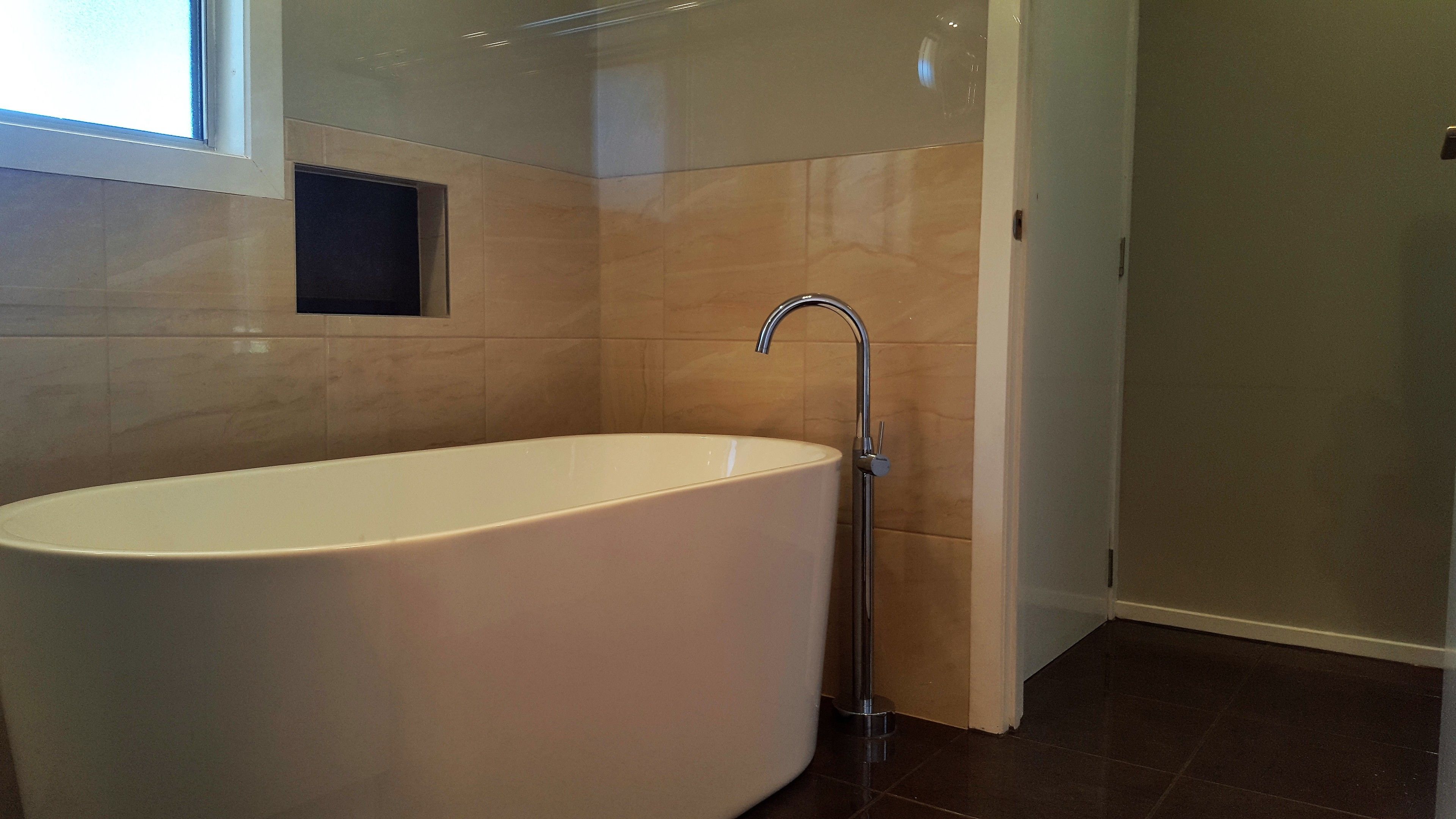 Un baño moderno con una bañera independiente, zona de ducha y ventana que proporciona luz natural.
