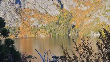 A mountainous landscape with a lake, surrounded by autumn-colored trees.