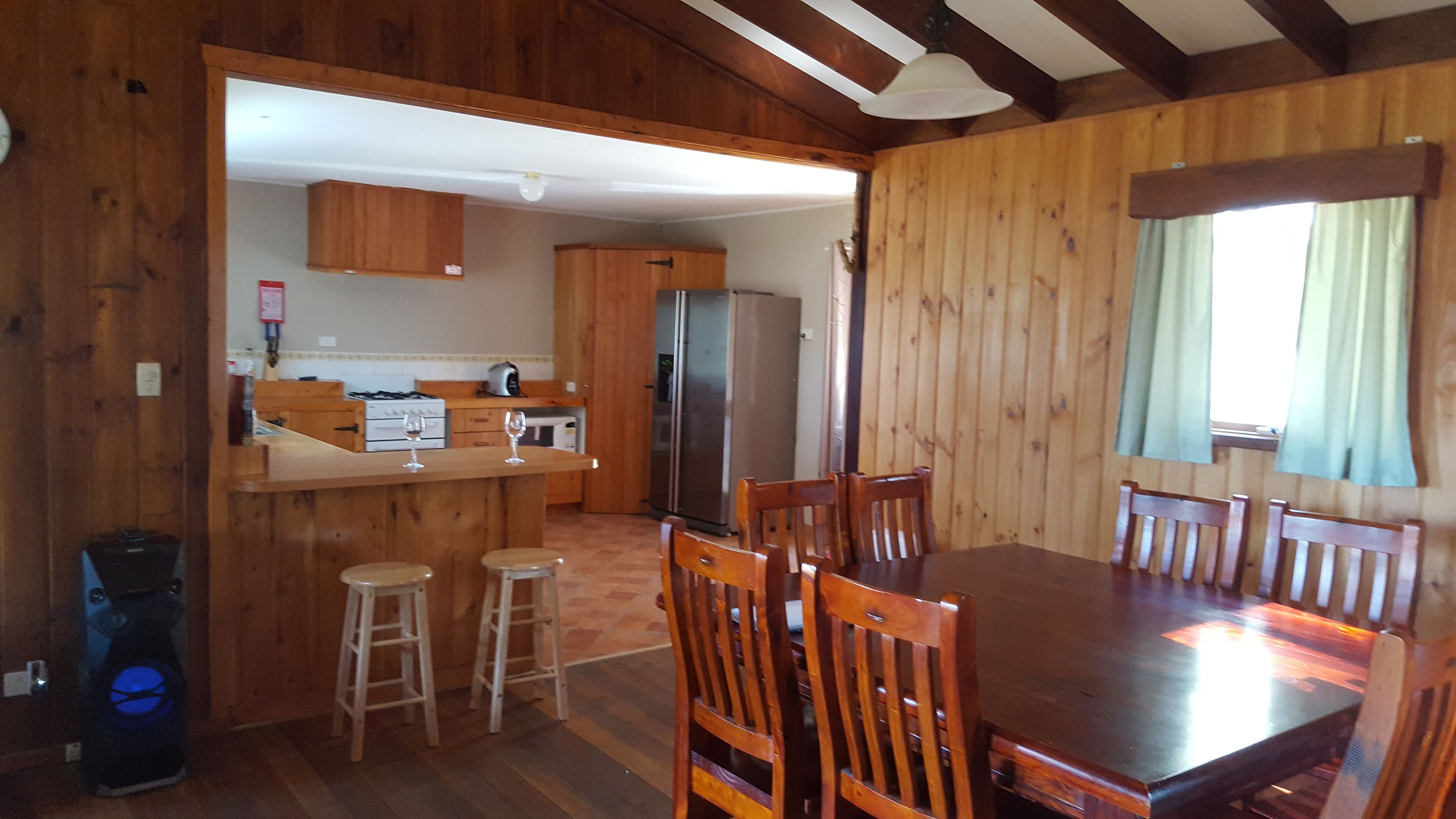 A wooden interior with a kitchen, dining area, and a refrigerator.