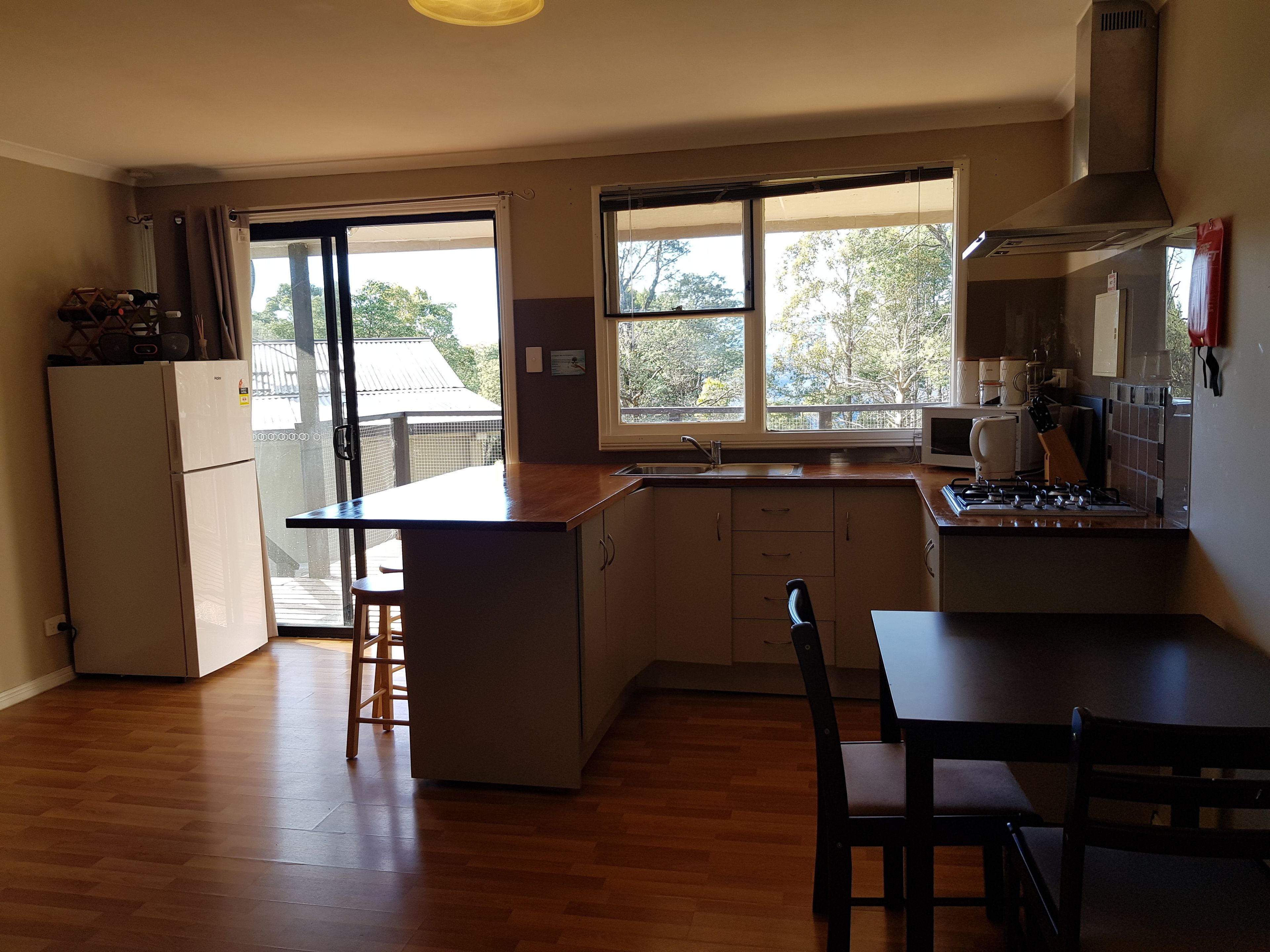 Une cuisine dotée d’un plan de travail en bois, d’une cuisinière, d’un réfrigérateur et d’une fenêtre donnant sur un balcon.