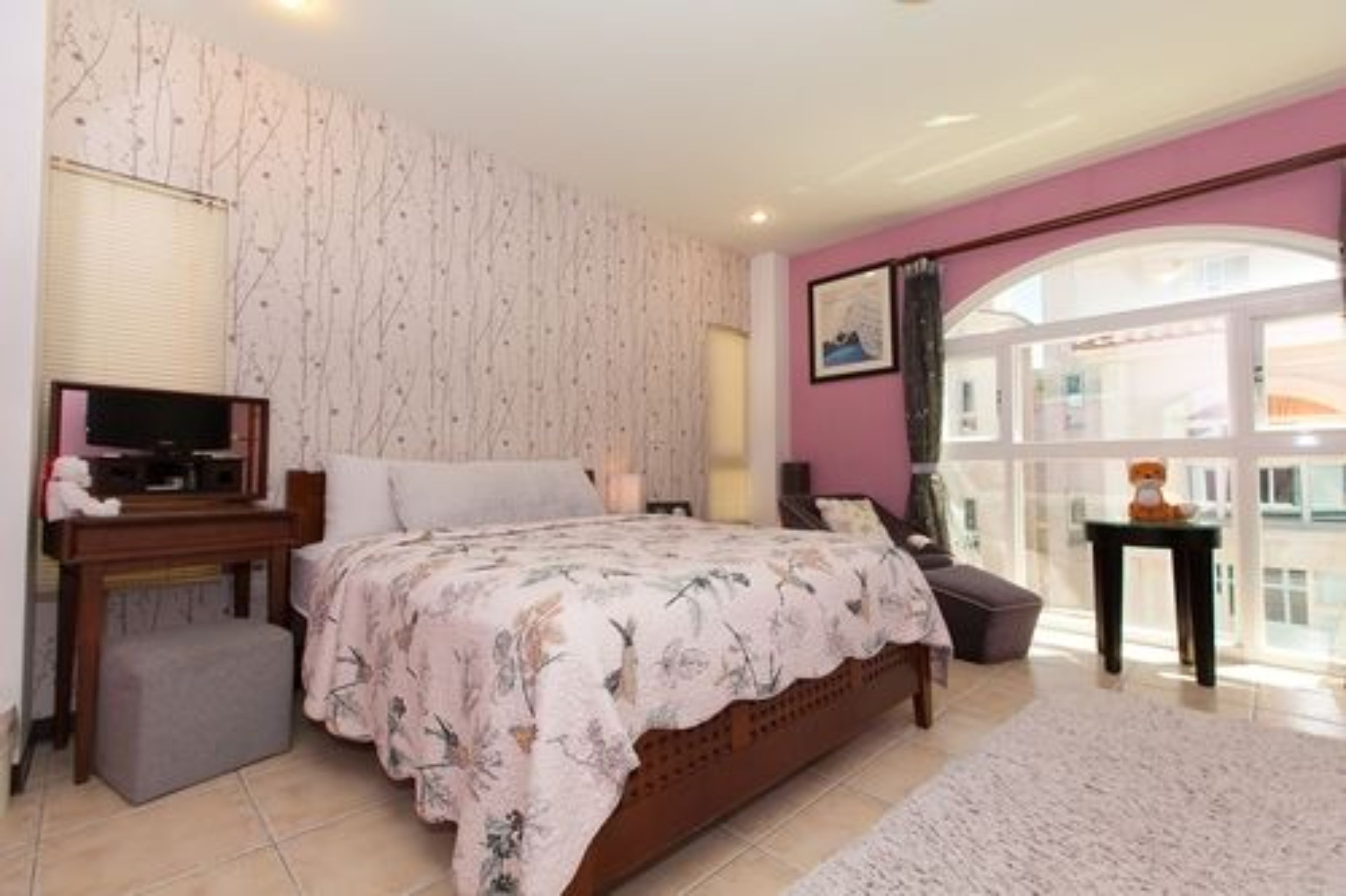 Een slaapkamer met een bed, nachtkastje en een raam met uitzicht.