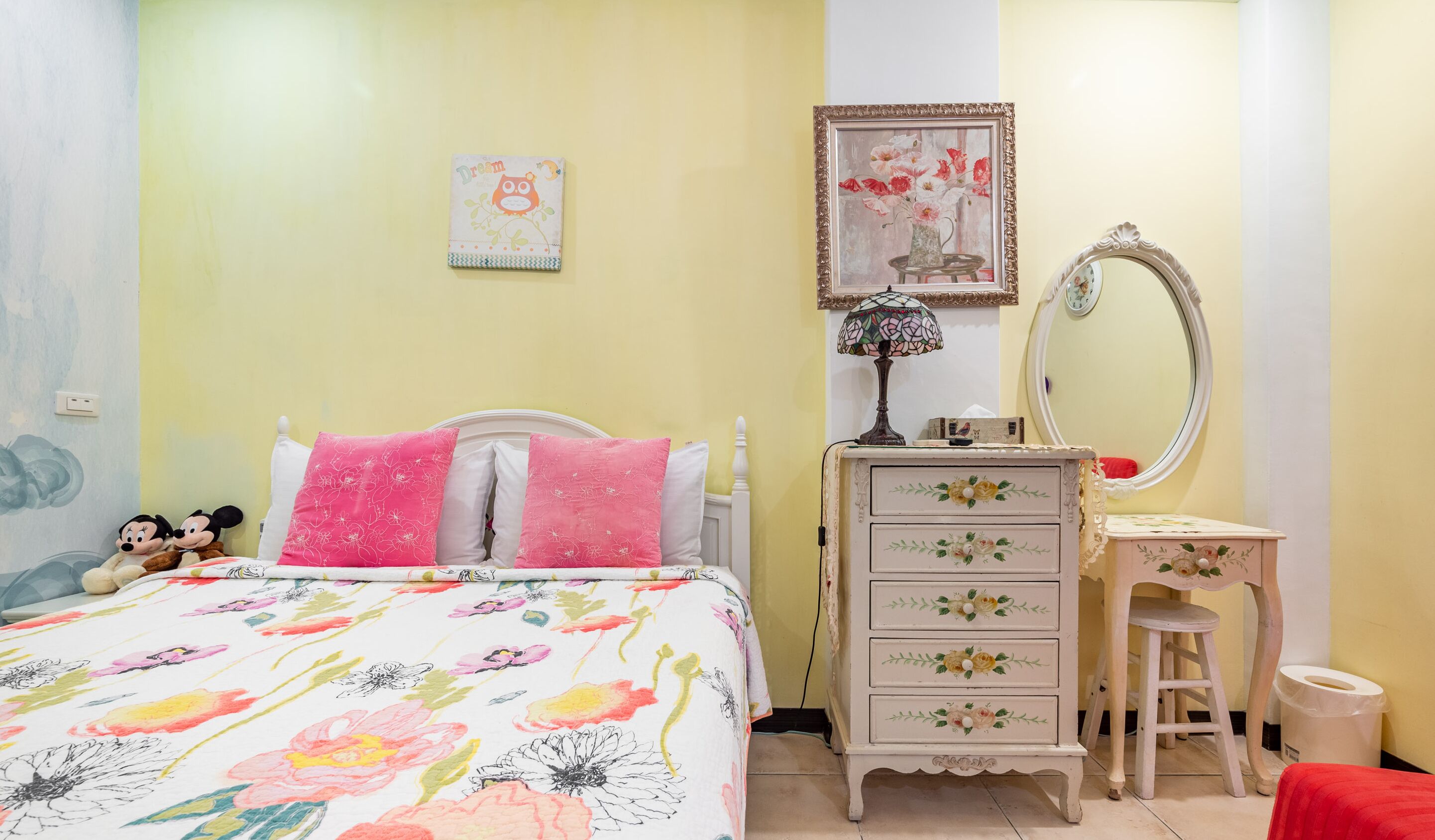 A bedroom with a bed, a dresser, a mirror, and a wall with a painting.