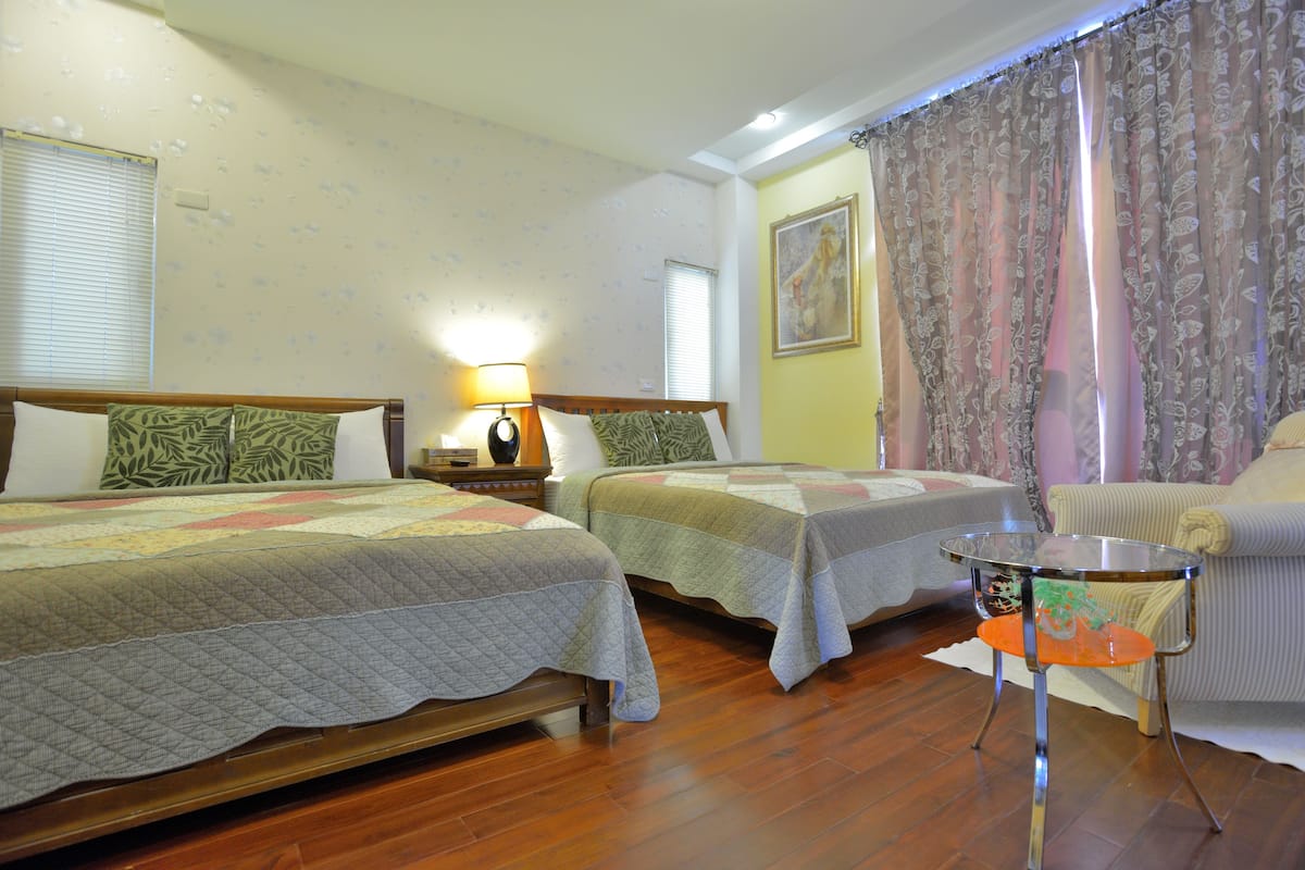 A hotel room with two beds, a small table, and a chair.
