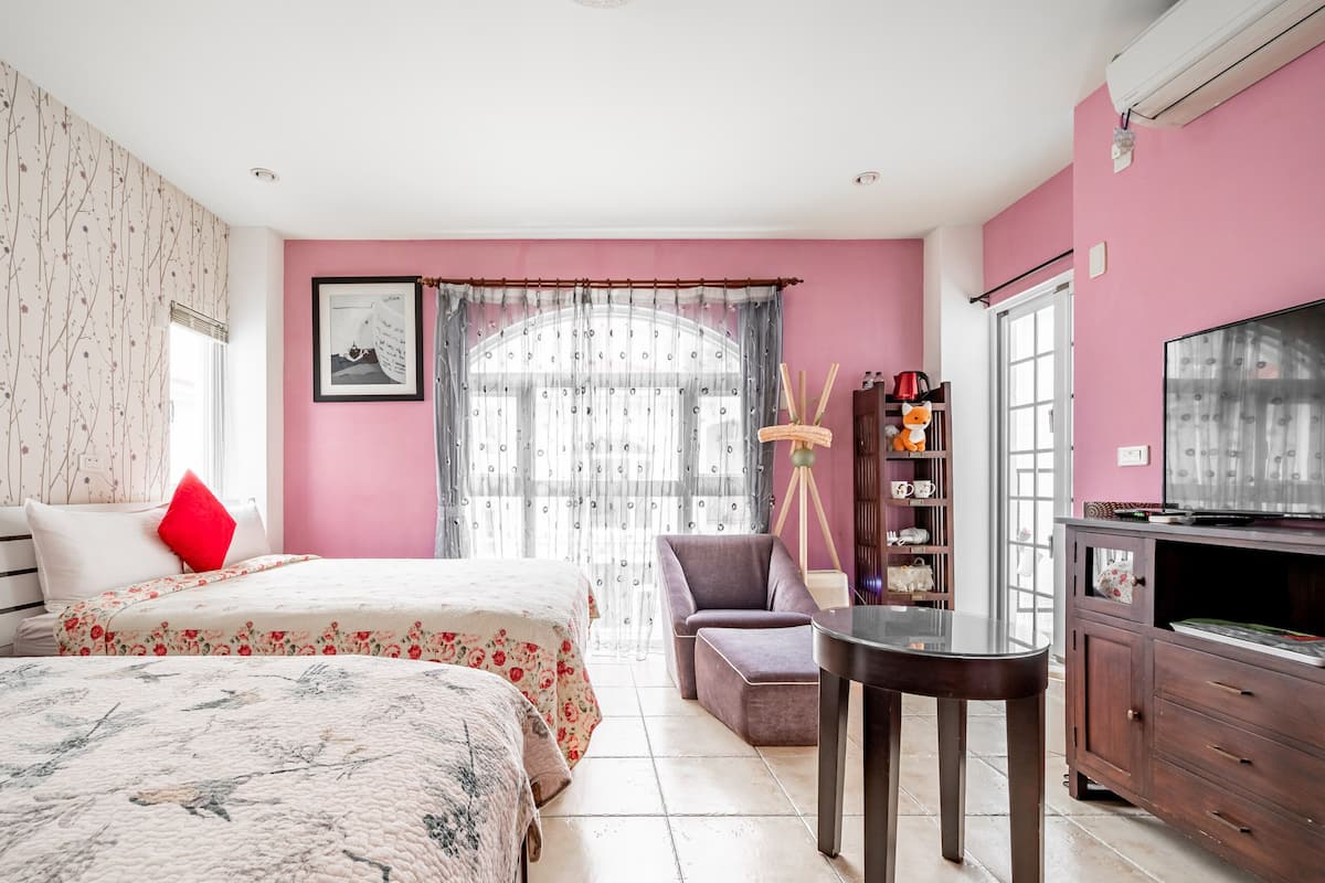 A hotel room with two beds, a desk, a chair, a TV, and a wardrobe.