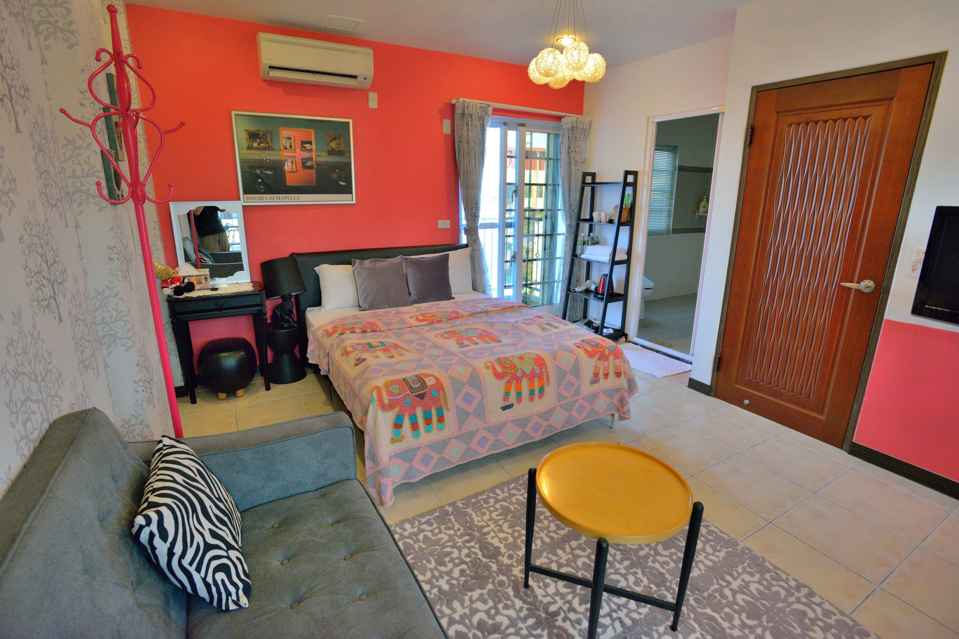 A bedroom with a bed, a sofa, a chair, a desk, and a wardrobe.