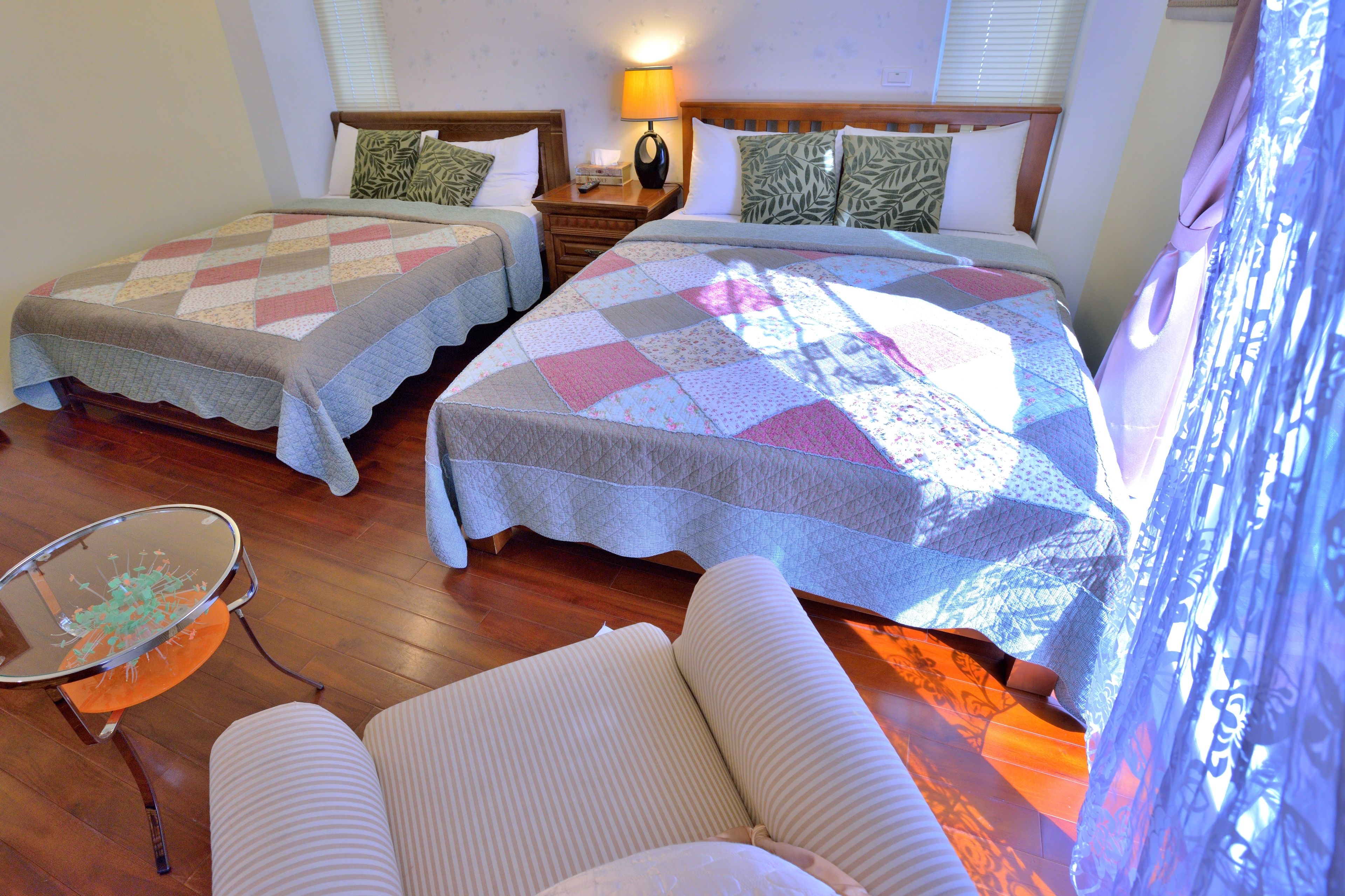 A hotel room with two beds, a small table, and a chair.
