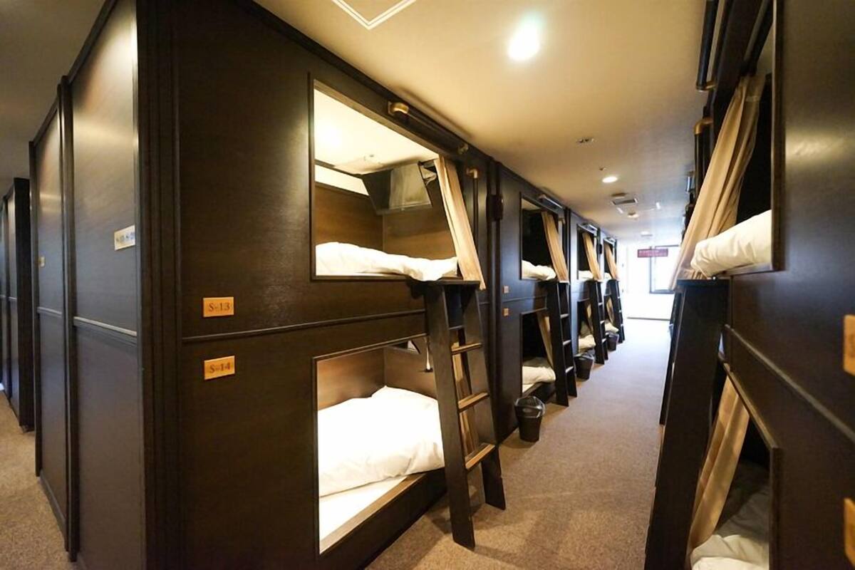 A train compartment with bunk beds, each with a small window and a headboard.