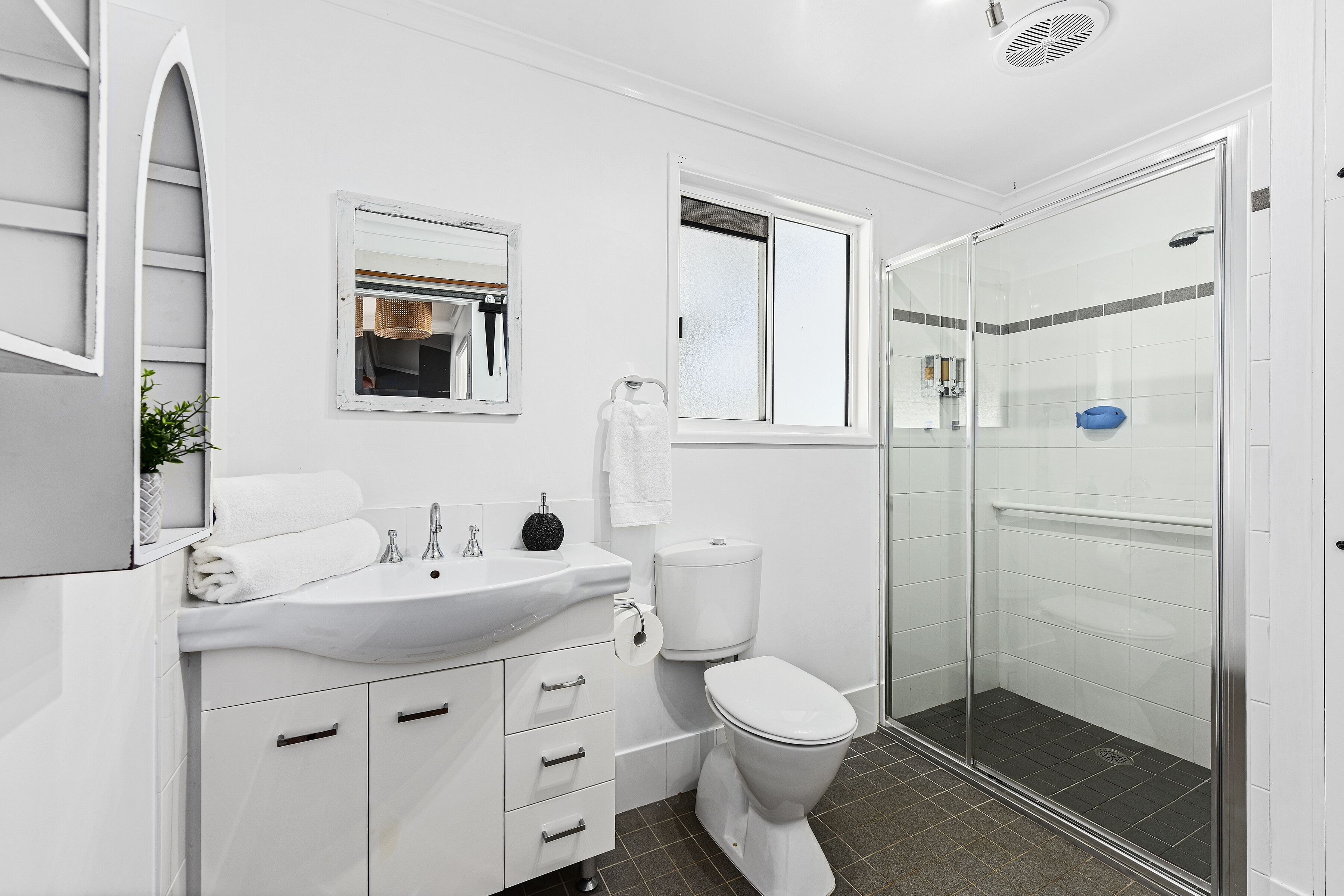 Ein modernes Badezimmer mit Waschbecken, Toilette und Dusche, alles in Weiß.