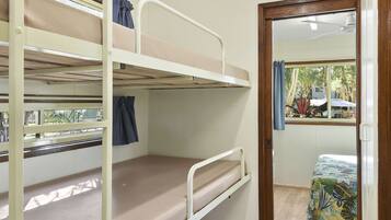 A bunk bed room with a window, a door leading outside, and a small table with a chair.