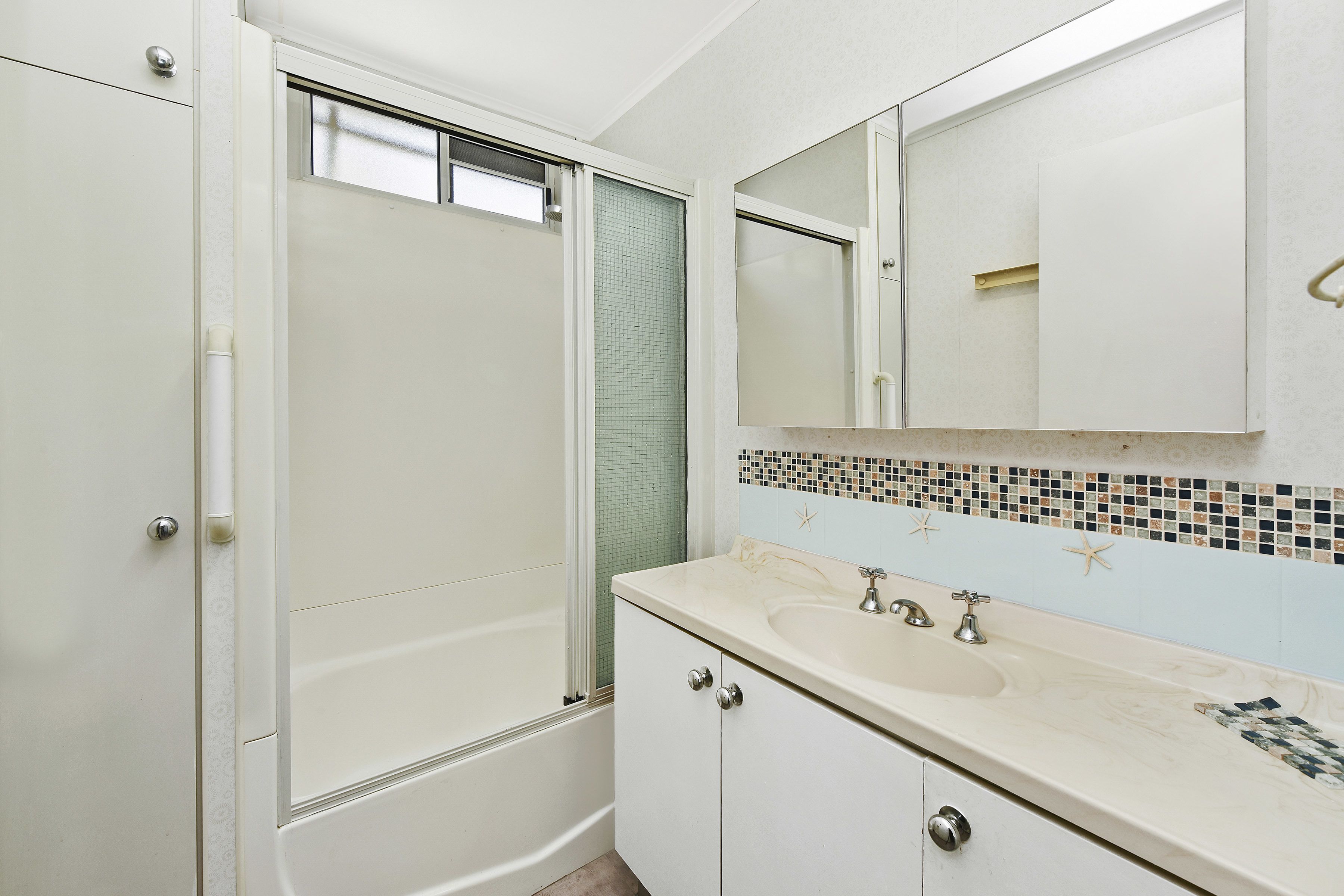 Un baño con ducha, lavamanos y espejo.