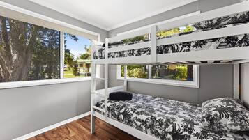 Une chambre avec des lits superposés, donnant sur des arbres et un bâtiment à l’extérieur.